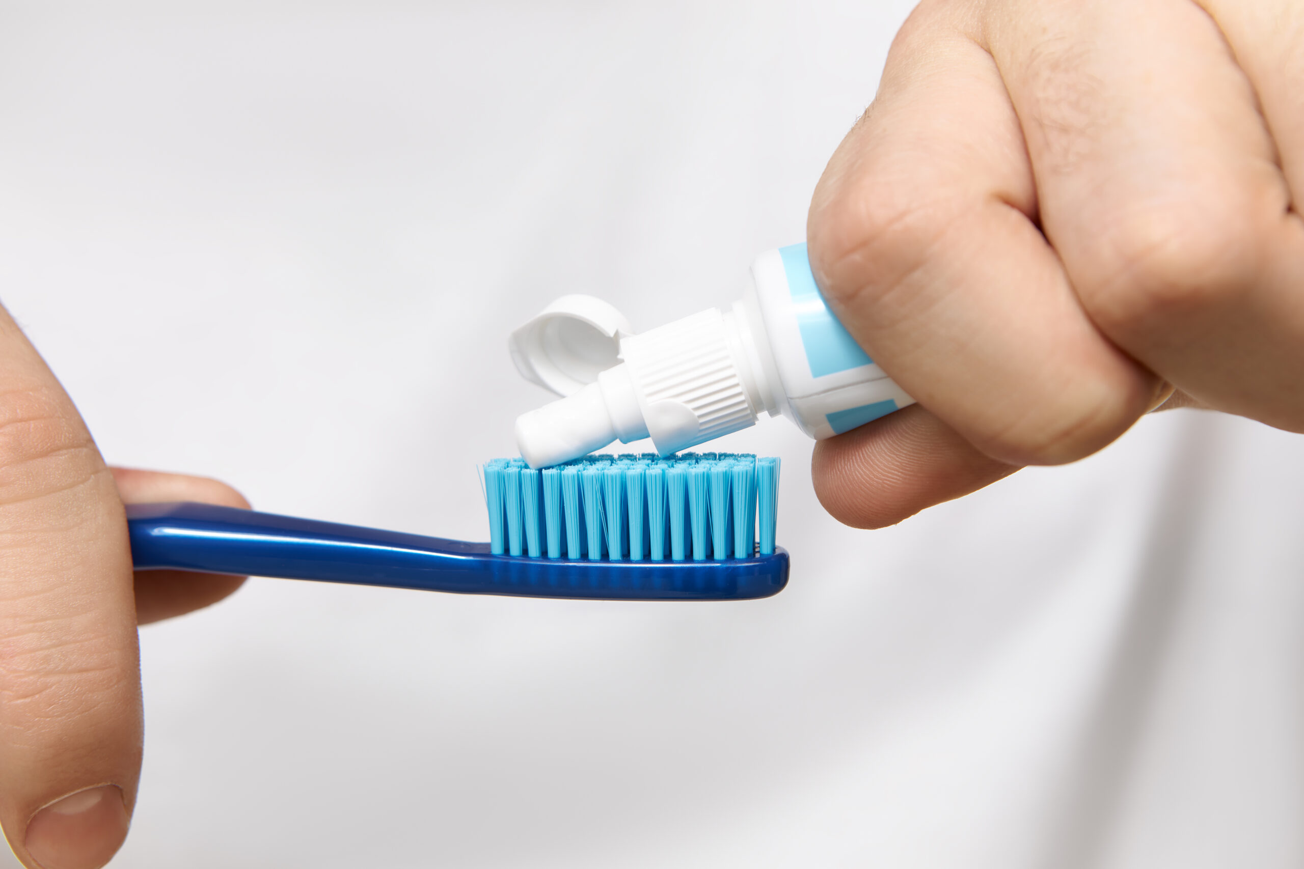Close up image of man's hands holding tube, squeezing whitening toothpaste on brush. Cropped shot of young male going to clean oral cavity after having meal. Hygiene, care and healthy lifestyle